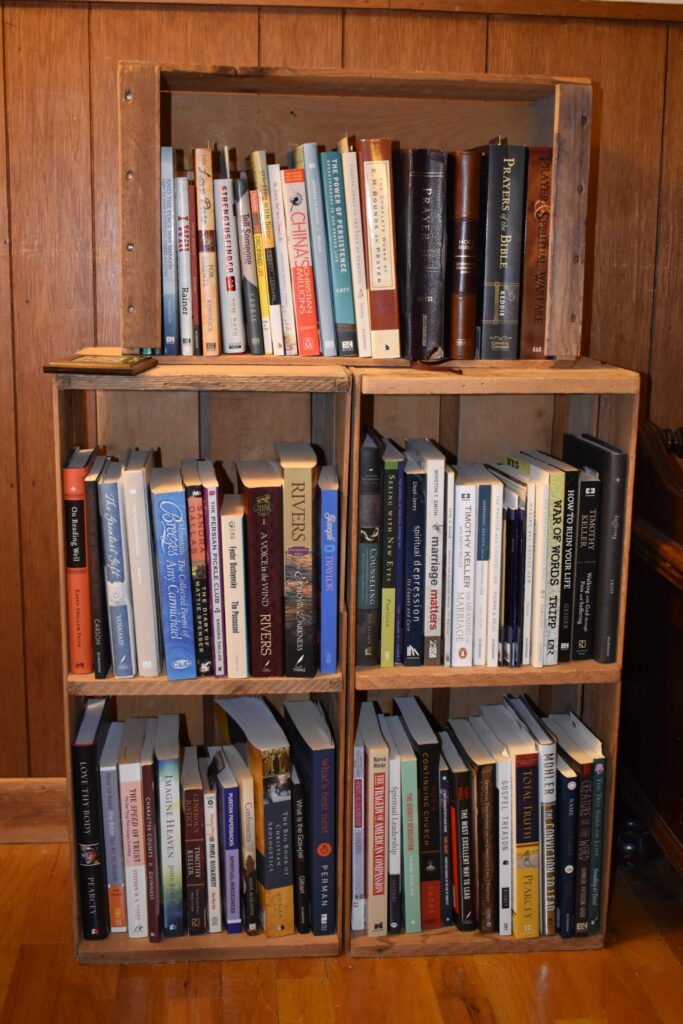 A collection of 5 old wooden crates hold a collection of old books.